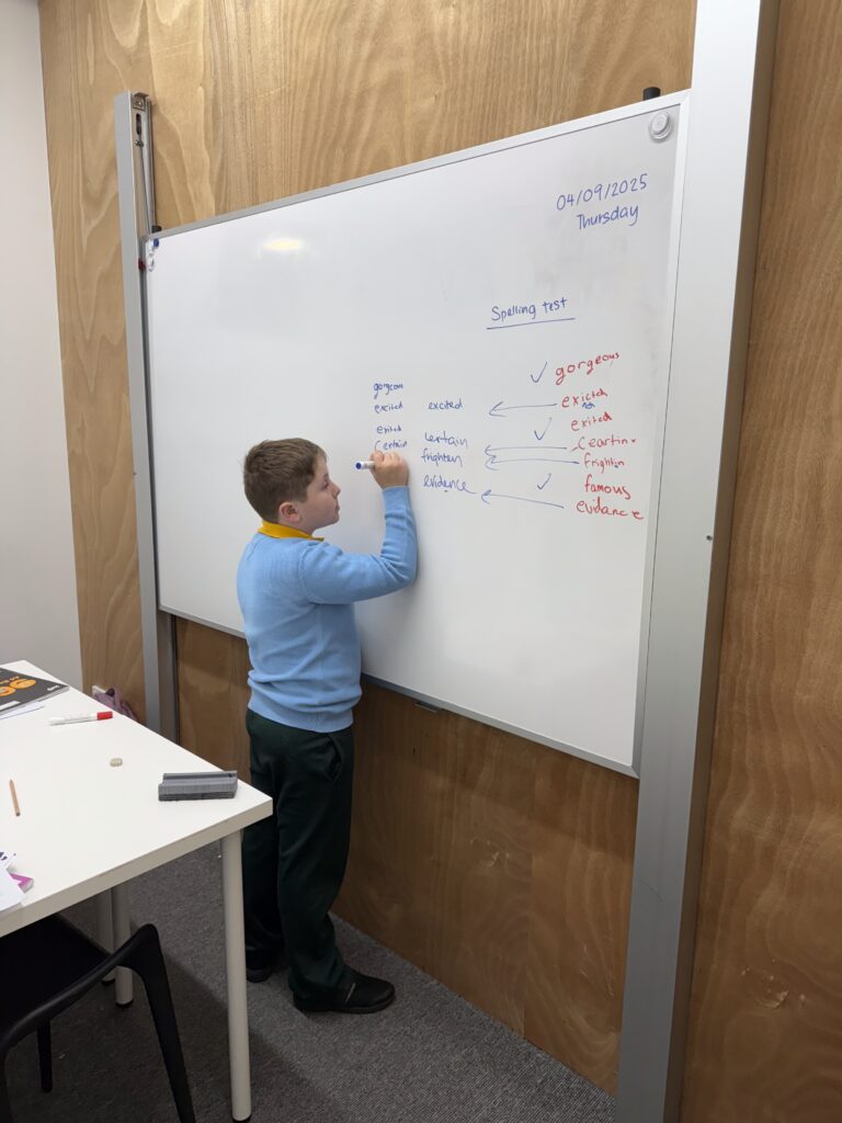 Young Boy Doing Spelling Test on Whiteboard