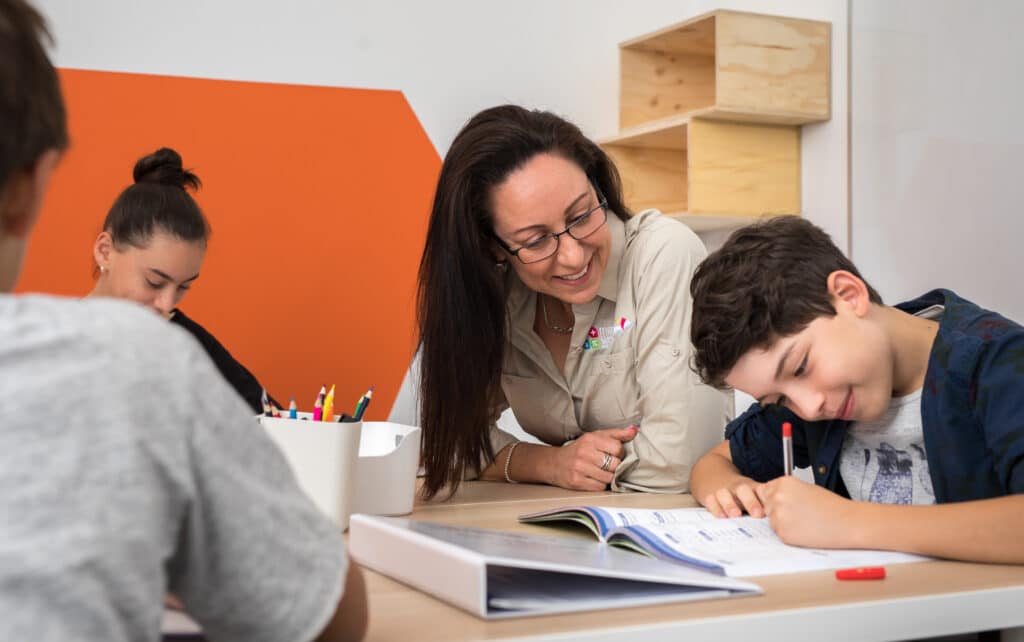 Tutor Smiling at Young Boy Writing