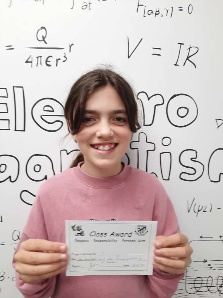 Young student proudly holding her certificate of achievement at school